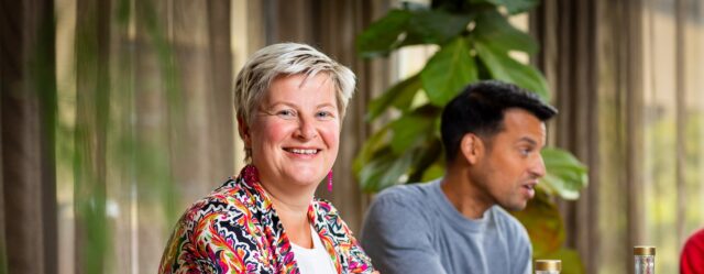 Vrouw kijkt lachend, en is in gesprek met anderen