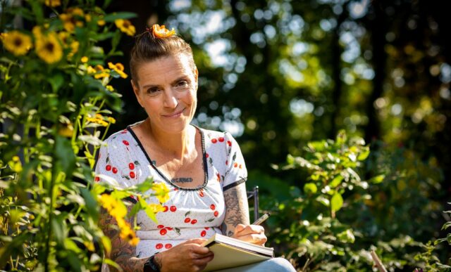 vrouw met kort haar zit tussen de bloemen